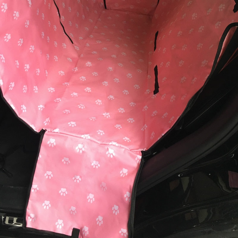 Back seat automotive pet cover in pink with white paw prints.