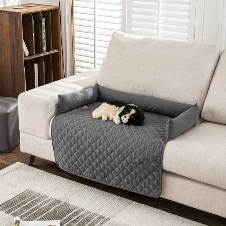 gray partial patterned couch cover with bolsters and dog on top