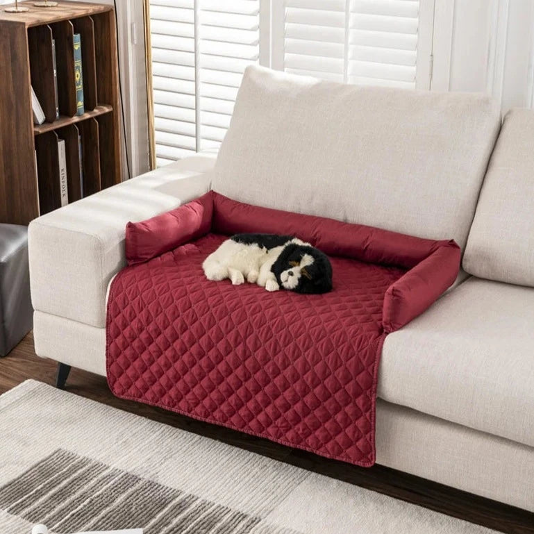 red partial patterned couch cover with bolsters and dog on top