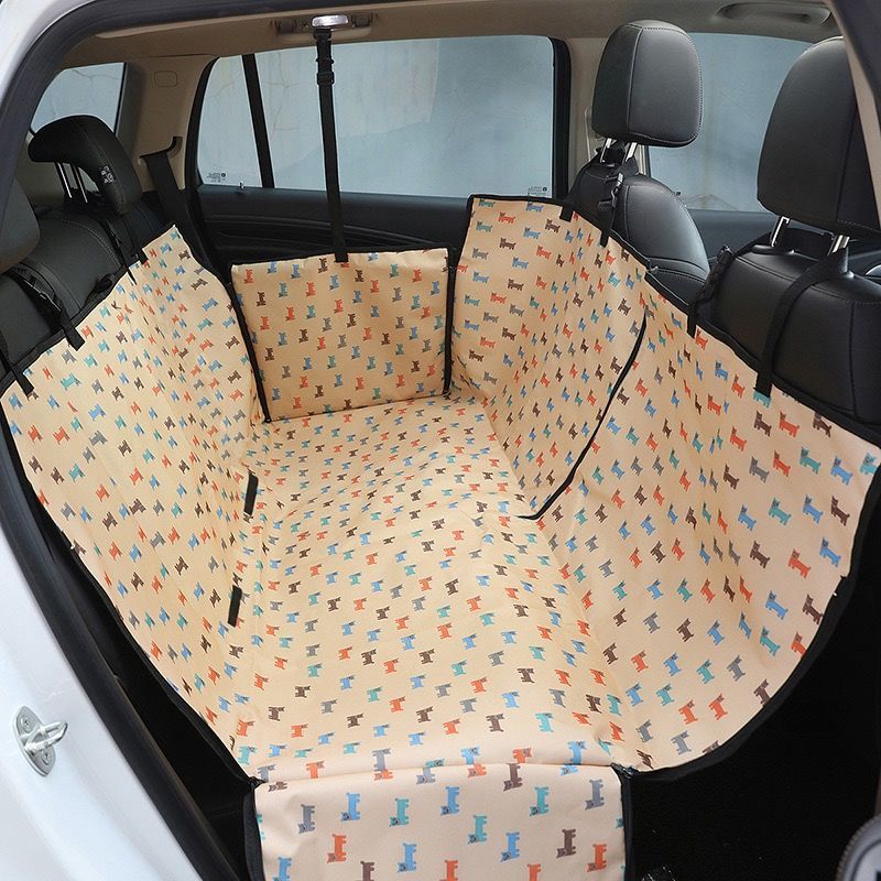 Back seat automotive pet cover in peach with dog prints.